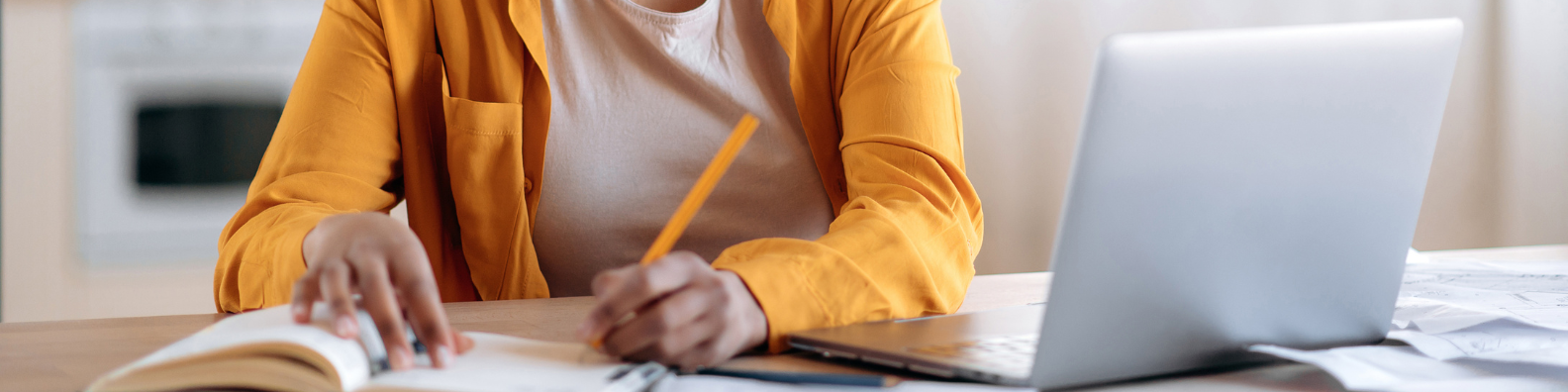 Someone looks at a laptop and writes notes. 