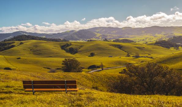 A bench seated on a plain overlooking more hills and plains
