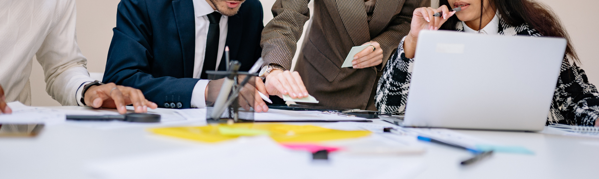 An image of coworkers brainstorming over a table covered with notes and laptops.